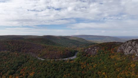 Una-Vista-Aérea-Sobre-Las-Montañas-En-El-Norte-Del-Estado-De-Nueva-York-Durante-El-Cambio-De-Follaje-De-Otoño,-En-Un-Hermoso-Día-Con-Nubes-Blancas