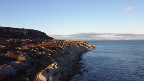 4K-Aerial-panoramic-landscape-shot-of-cliffs-on-the-island-of-Portland-during-sunset,-flying-over-the-beach-of-Church-Ope