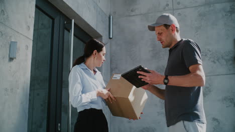 customer receiving package and signing on tablet from delivery person