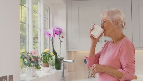 Rentnerin-Steht-Zu-Hause-Am-Fenster-In-Der-Küche-Und-Trinkt-Kaffee