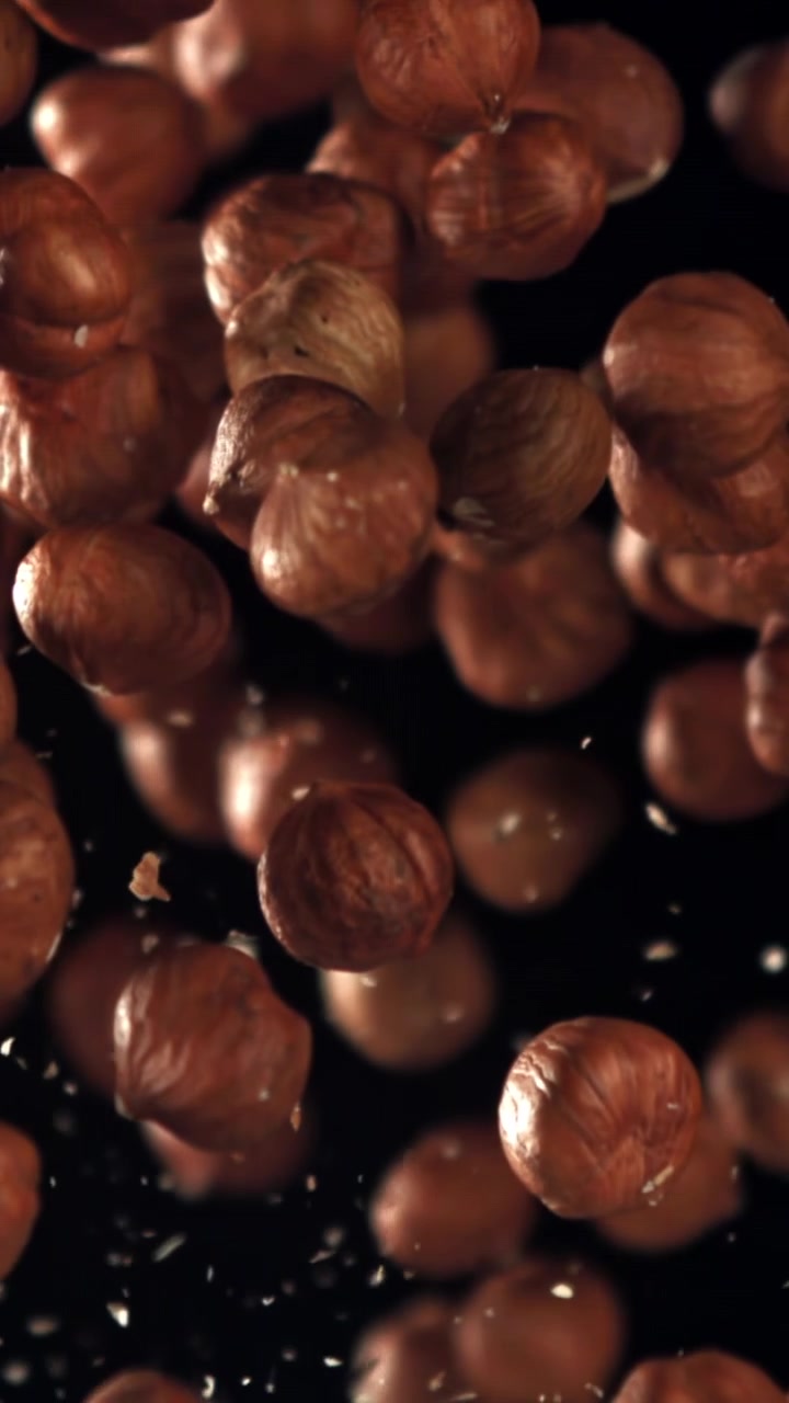 Nocciole pelate che galleggiano al rallentatore su sfondo nero