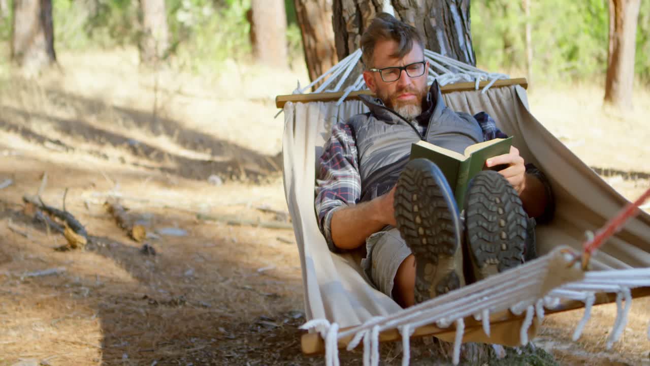 Uomo che legge un libro mentre si rilassa su un'amaca 4k
