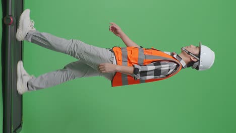 안전 헬을 입고 녹색 스크린 배경 스튜디오에서 고 있는 아시아 남성 엔지니어.