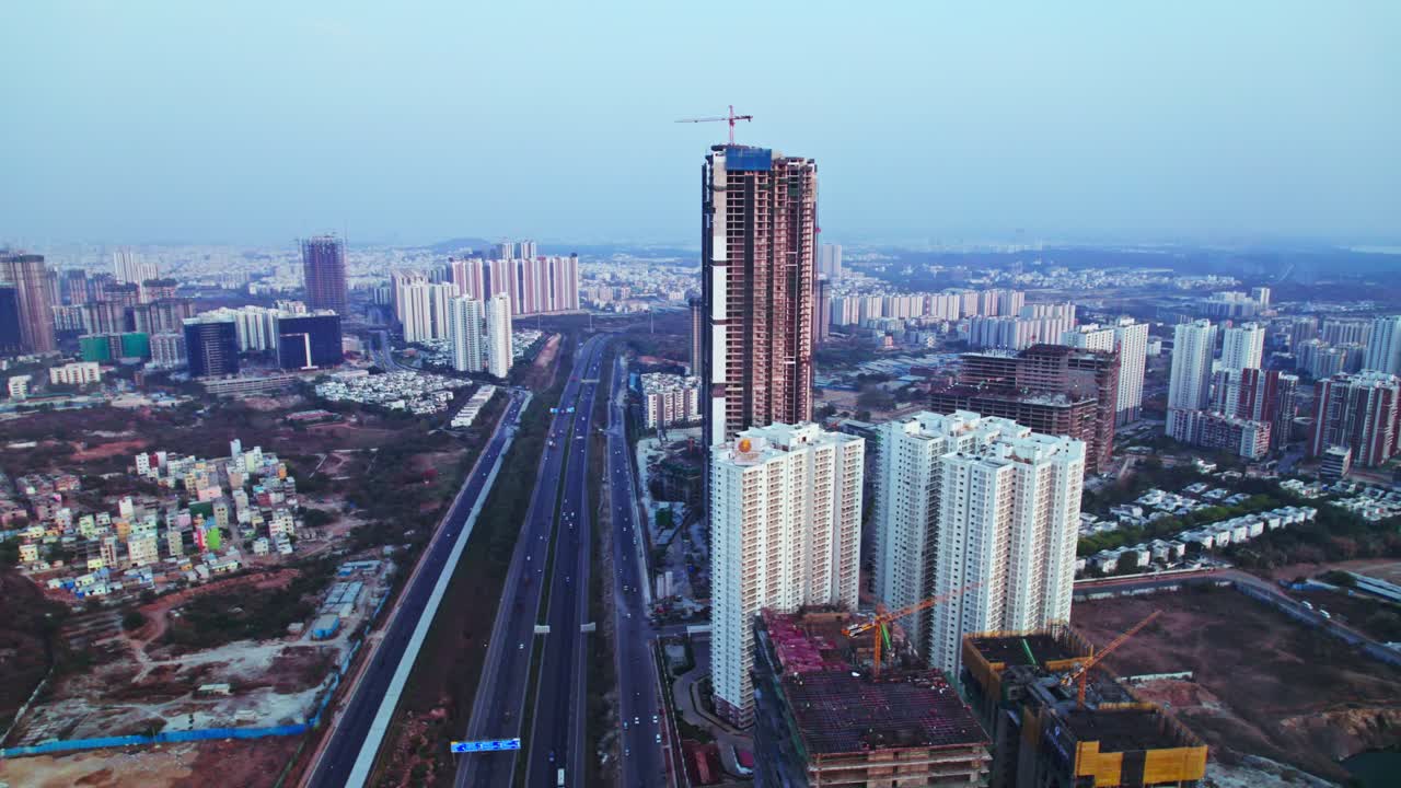 Tallest under construction building with crane construction and outer ring road at financial district, nanakramguda, hyderabad, telangana, india. day time, pan shot, drone shot, 4k.