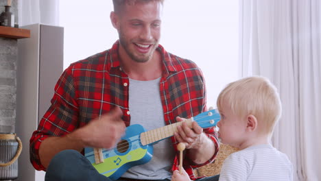 father playing ukulele to toddler son, close up