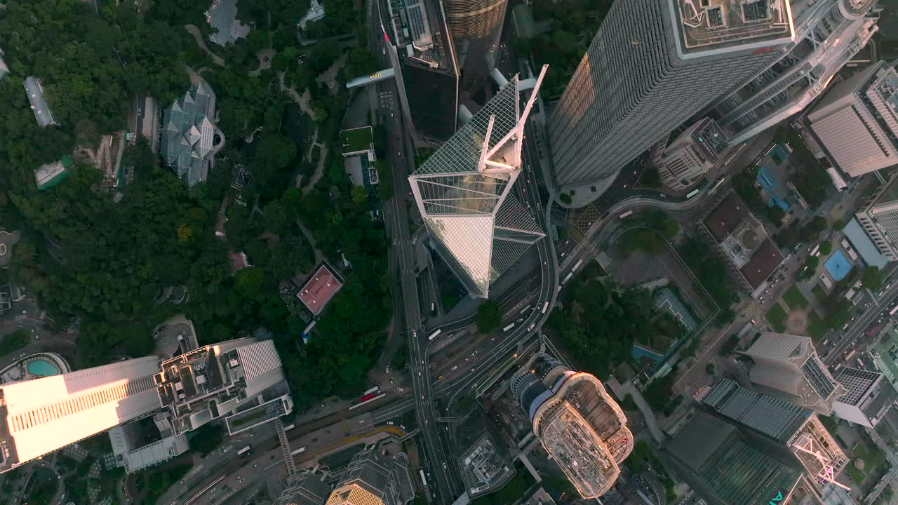 Tomada aérea de cima para baixo mostrando o trânsito na autoestrada perto do Banco da China no centro de Hong Kong ao pôr do sol.