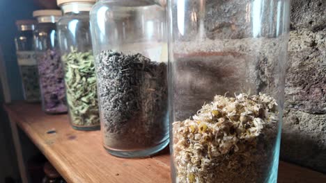 dried herbs in glass jars on a wooden shelf