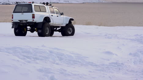 Tilt-up,-white-super-jeep-overlooking-ocean-and-mountain-scene,-Iceland