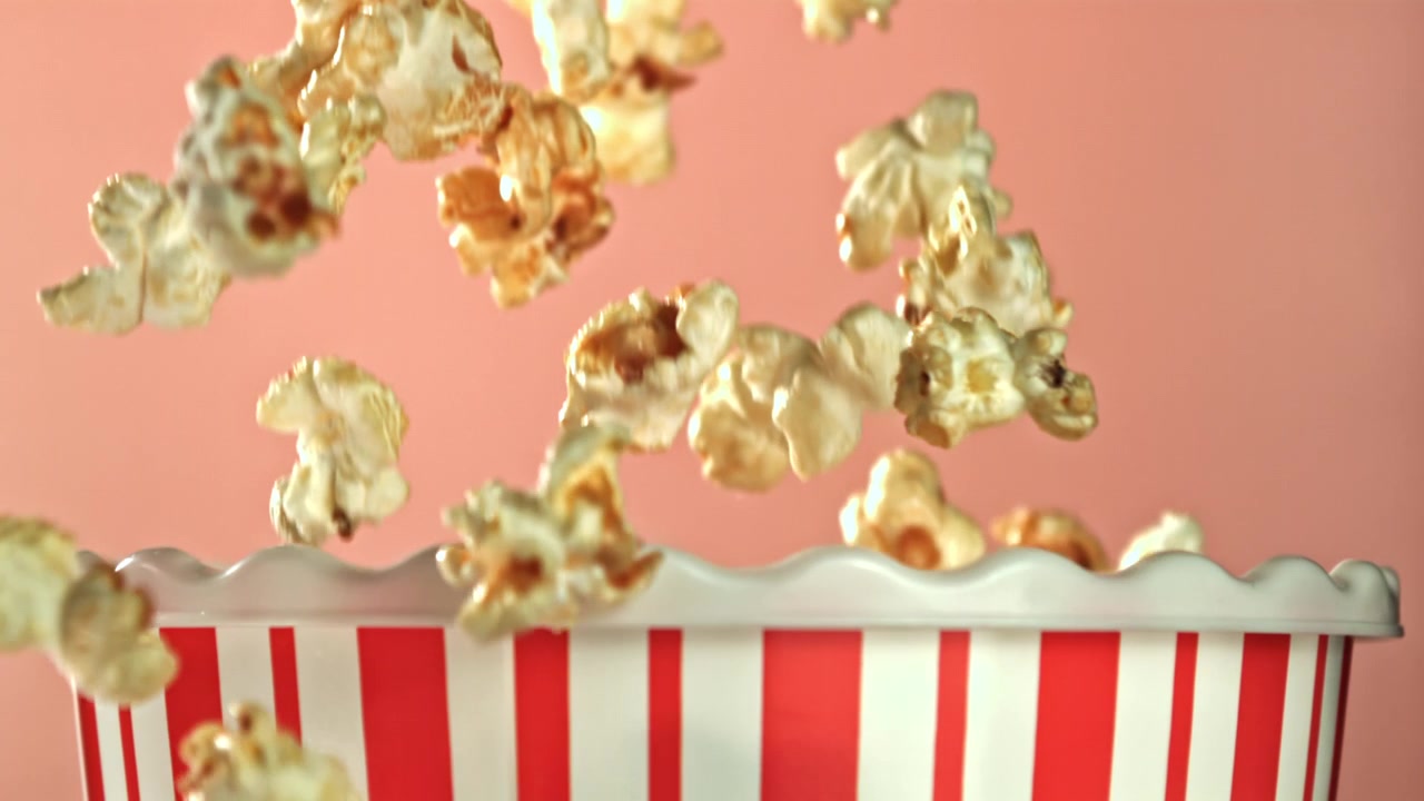 Popcorn che cadono al rallentatore in una scatola a strisce rosse e bianche.