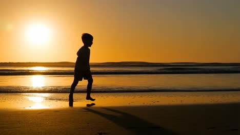 child's golden silhouette on a sunset beach