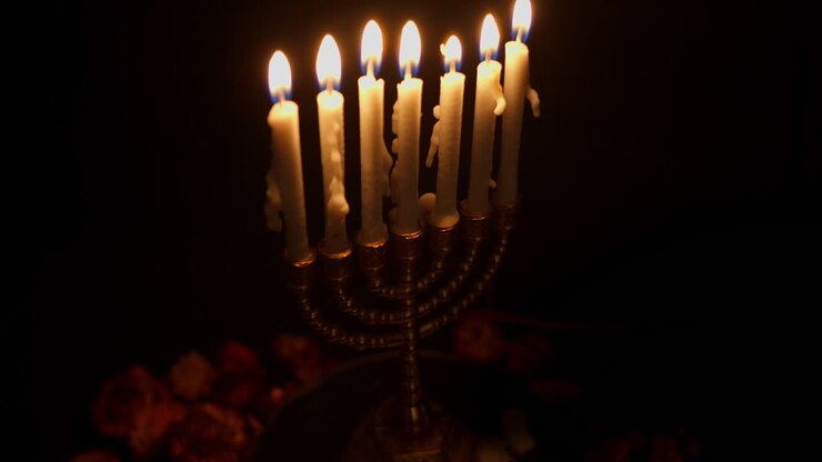 Golden Menorah with Lit Candles Burning in the Dark