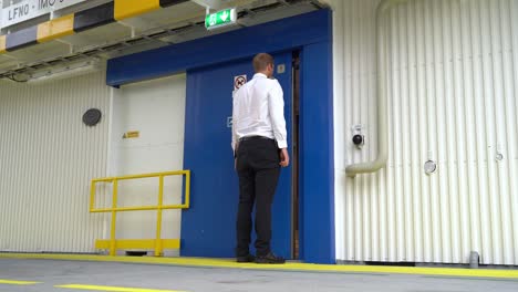 Officer-in-uniform-walking-across-ferryboats-car-deck-and-opening-sliding-door-to-passenger-area---Low-angle-static