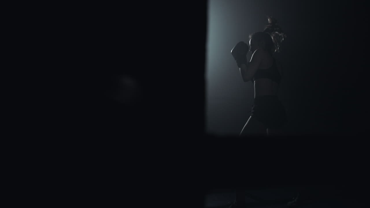 Woman Training Boxing in Dark Gym with Dramatic Lighting