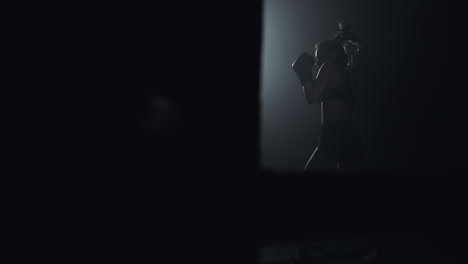 woman training boxing in dark gym with dramatic lighting