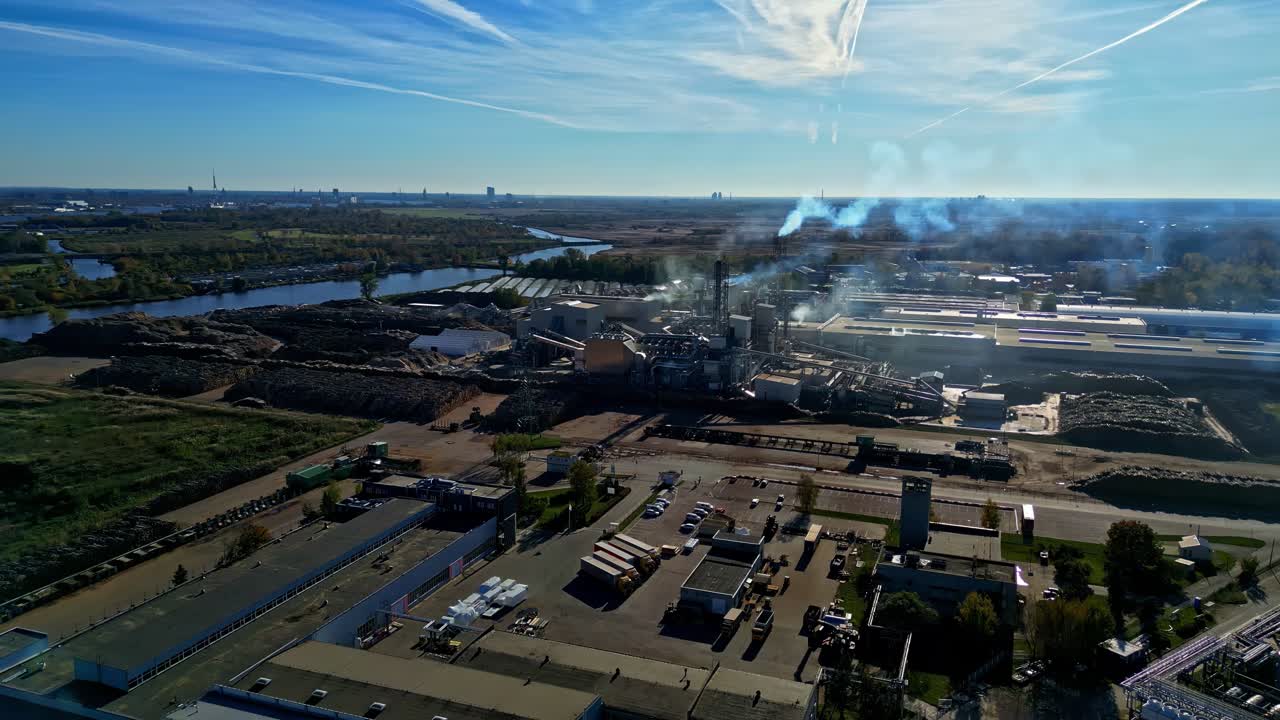 Vista aerea di un'area industriale con ciminiere fumanti accanto a un fiume