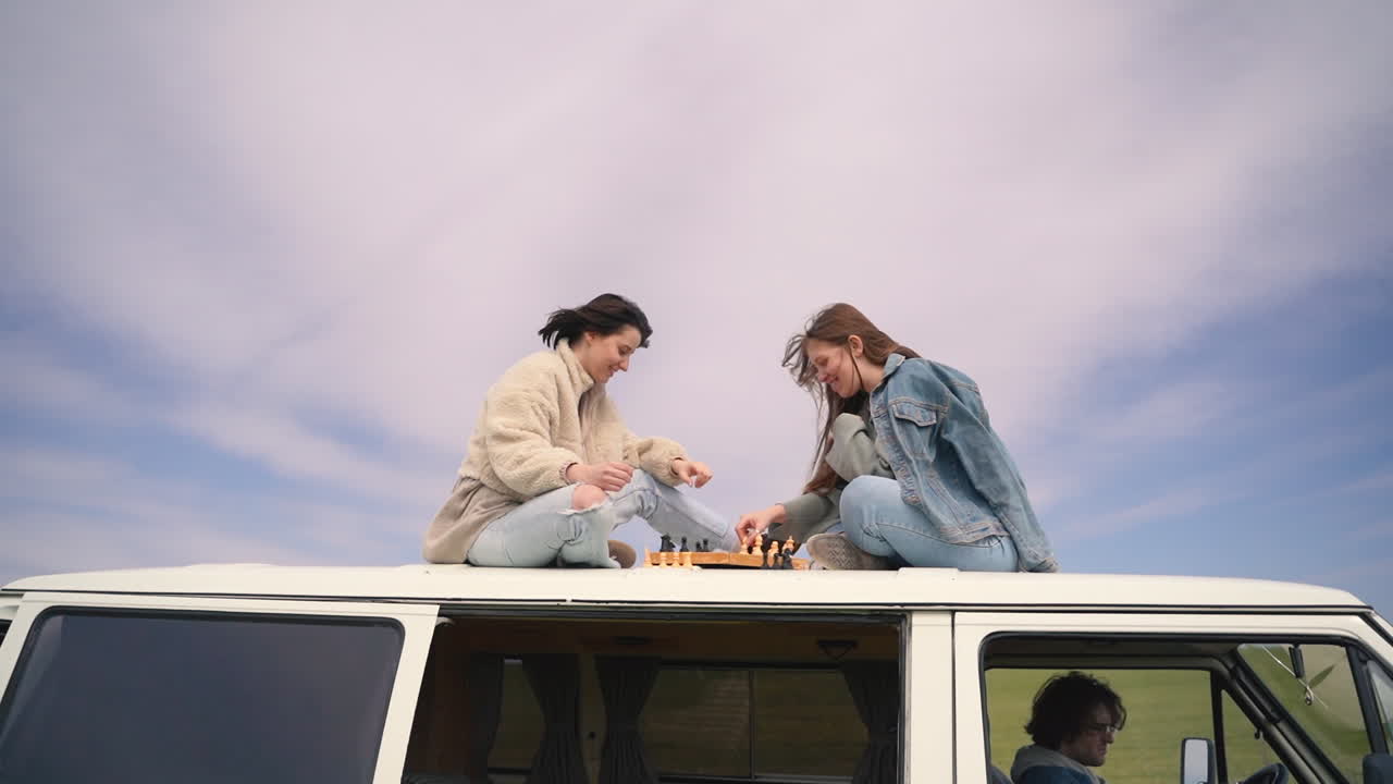두 어린 소녀가 시골 한가운데서 길을 잃은 캐러밴 지붕에서 체스를 두었습니다.