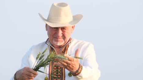 Portrait of a senior man in traditional clothing holding wheat