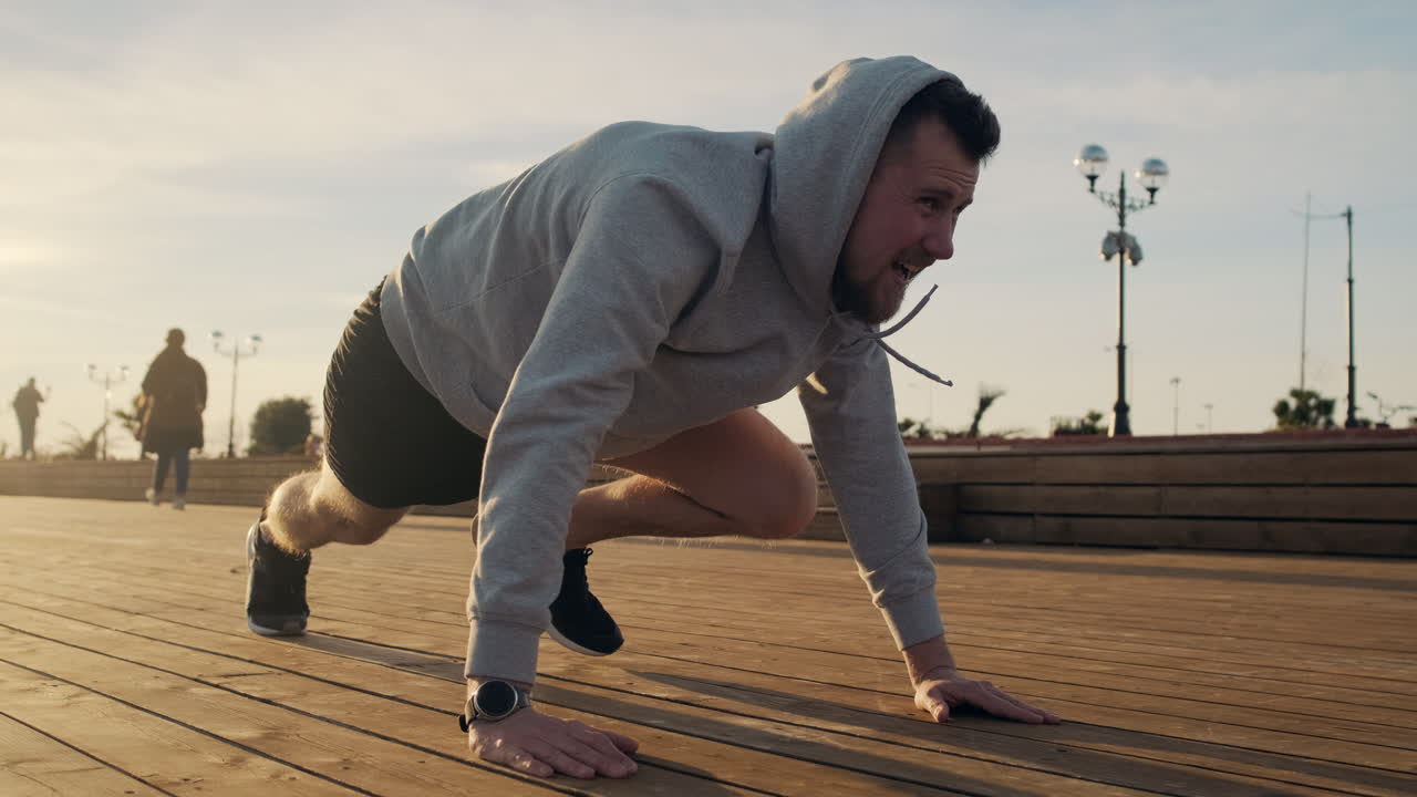 Man doing push-ups on a boardwalk at sunrise/sunset