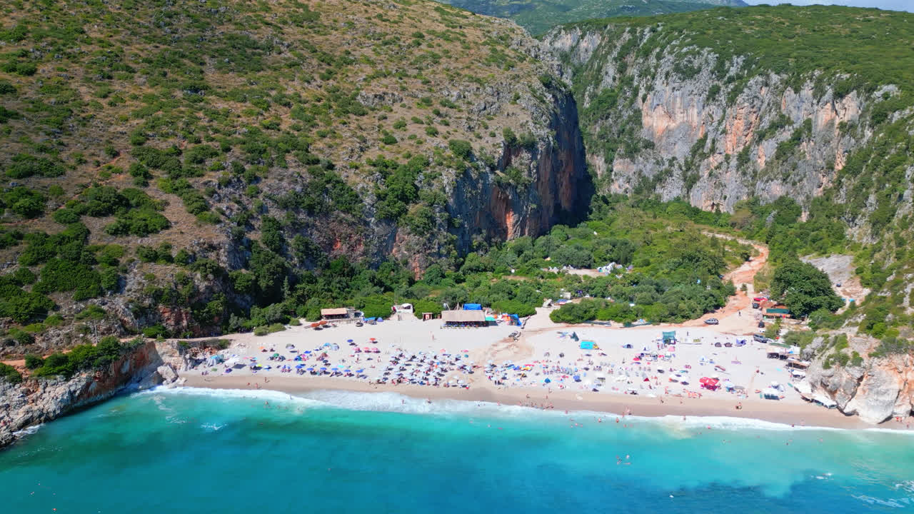 Aerial drone forward moving shot flying high over secluded Gjipe beach, Albania on a sunny day
