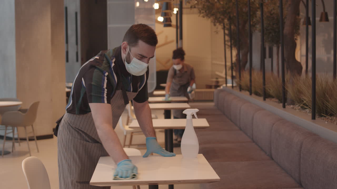 Caucasian Waiter Wiping Table in Restaurant