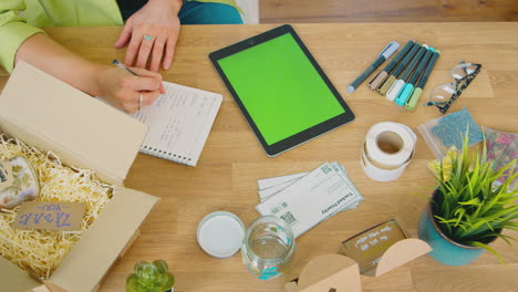 overhead shot of woman running online business making candles packaging them for dispatch