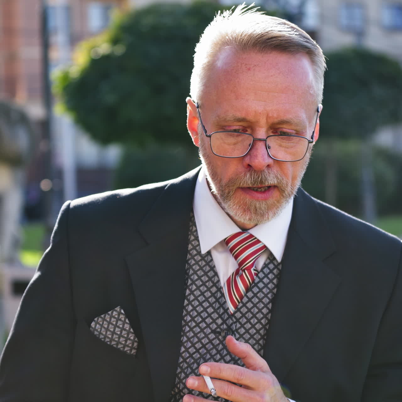 Thoughtful mature man smoke outdoors. Nervous middle aged businessman in glasses smoking cigarette standing on the city background.