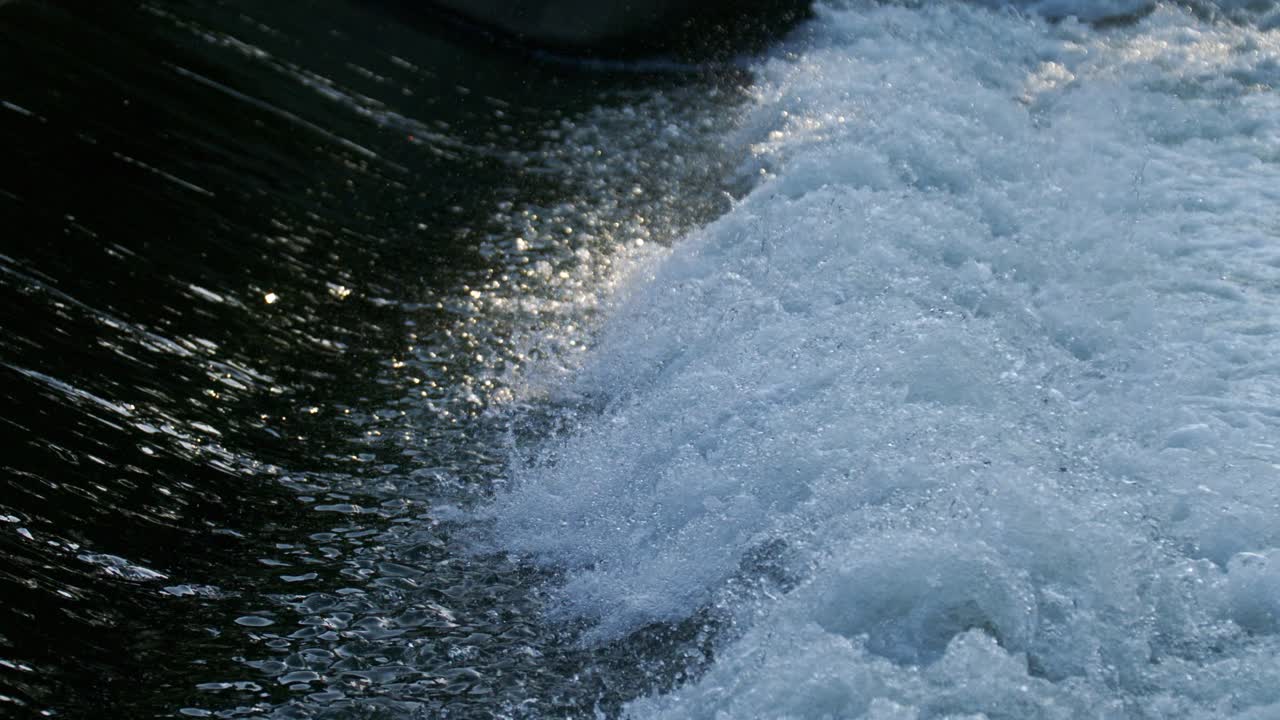 Super slowmotion of water stream flowing splashing with bubbles and reflections and shades