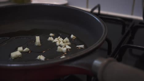 chef frying chopped garlic in olive oil, making italian soffritto