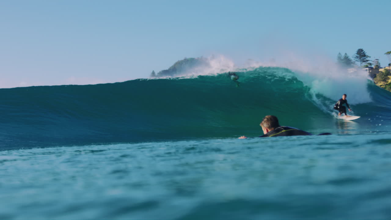 Slow motion view of surfer in water at surface level as the athlete balances and pullsback stalling into stunning barrel ride and bailing