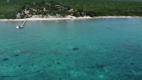 Luftaufnahme-Eines-Segelboots,-Das-Tagsüber-In-Der-Nähe-Der-Lebhaften-Küste-Von-Cozumel-Kreuzt,-Türkisfarbenes-Wasser