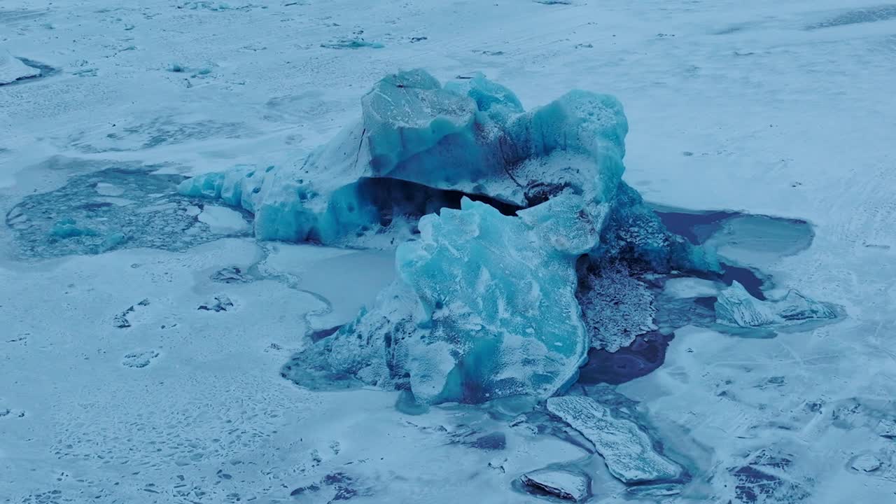 Aerial view over icebergs on the frozen Jokulsarl&oacute;n lake surface, in Iceland, at dusk