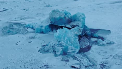 Aerial-view-over-icebergs-on-the-frozen-Jokulsarlón-lake-surface,-in-Iceland,-at-dusk