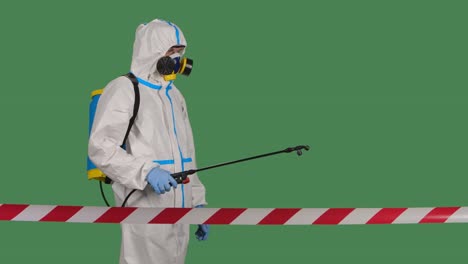 hombre en un traje de protección con una lavadora a presión desinfecta con spray antiséptico área peligrosa cercada con una cinta de señal roja y blanca. aislado en una llave de croma de pantalla verde. cerca. cámara lenta