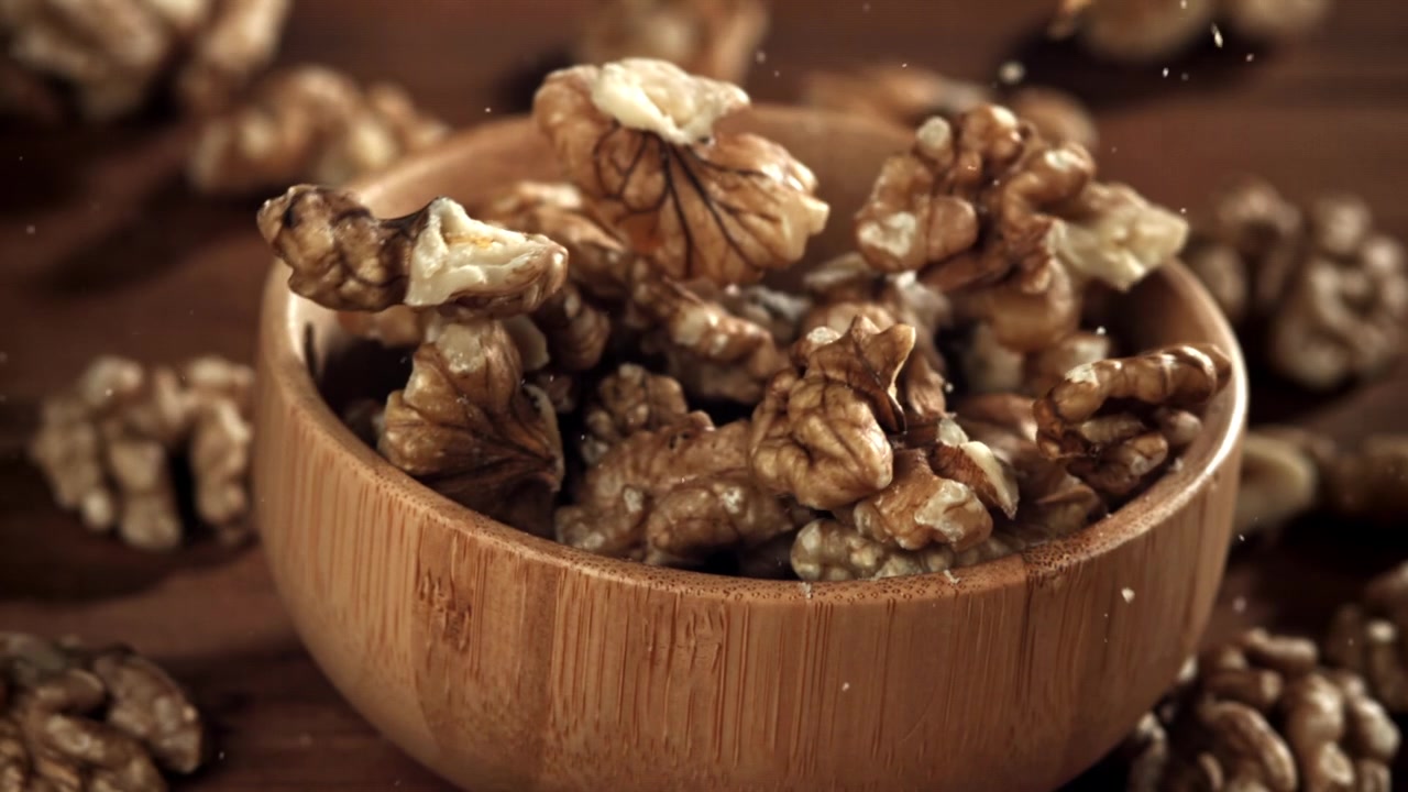 Slow Motion of Walnuts Falling into a Rustic Wooden Bowl