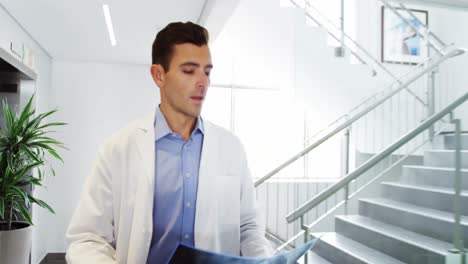 Doctor-and-nurse-discussing-over-x-ray-report-in-corridor