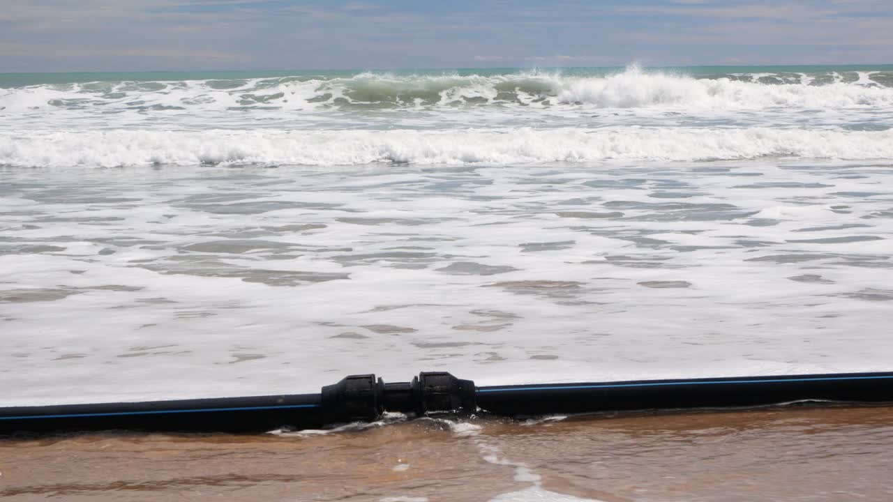 강한 폭풍 후 스페인 알리칸테 시 근처 로스 아날레스 델 솔의 해안선을 따라 씻겨진 검은색 파이프라인의 전망