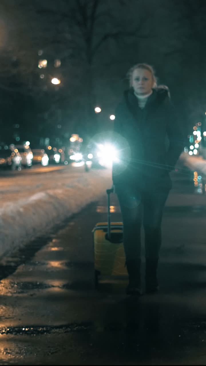 Woman Walking with Suitcase at Night in Snowy City