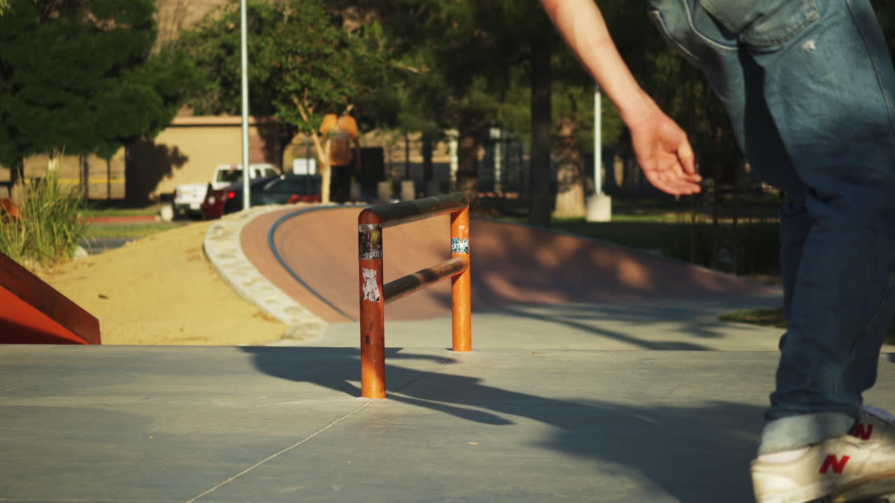 Skateboarder hops and slides along a rail at a skate park