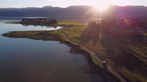 siguiendo un coche mientras conduce a lo largo de la orilla de un lago con una hermosa puesta de sol