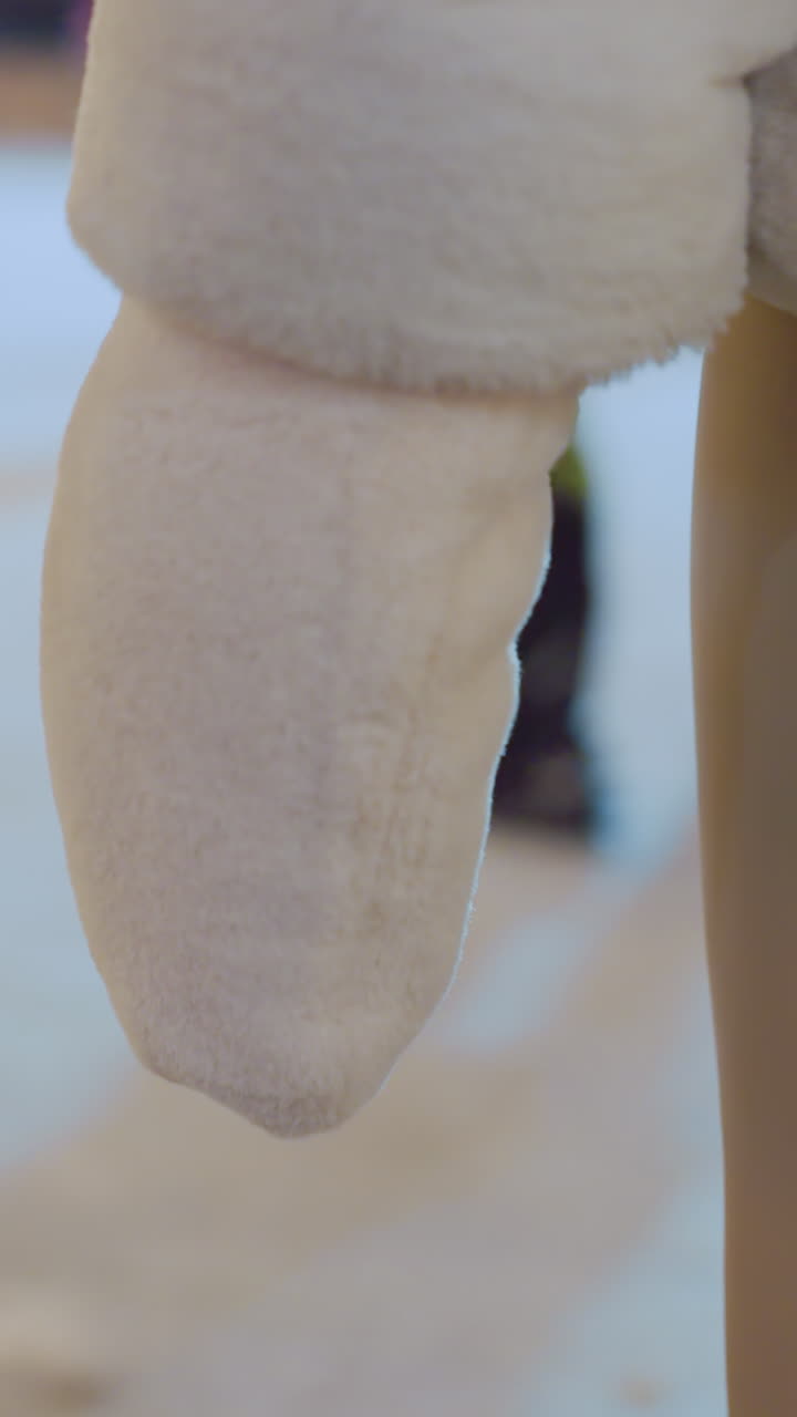 Rear view of person in brown trousers and winter coat standing still before gently turning around as people skate and move in the background during winter