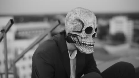 person in skull mask on a rooftop in black and white