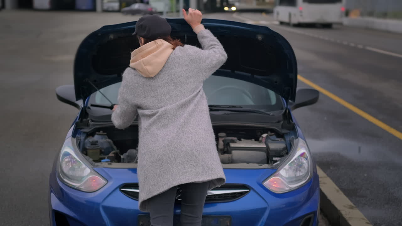 mujer arreglando un coche roto en el costado de la carretera
