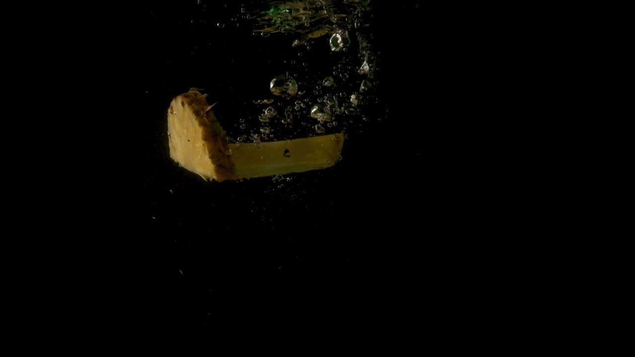 Two juicy healthy and fresh pineapple slices slowly drowning in the clear dark water