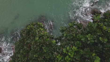 Dron-De-Vista-De-Pájaro-De-Camiones-Diagonales-En-La-Costa-Tropical-Con-Rocas-De-Granito-Y-Olas-Oceánicas-Y-Follaje-De-La-Jungla