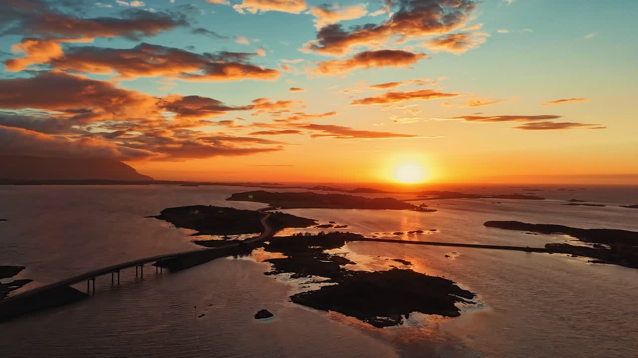 Jalan Samudra Atlantik, jembatan terkenal antar pulau dengan langit matahari terbenam terpantul di air tenang. Rekaman aerial time-lapse Norwegia.