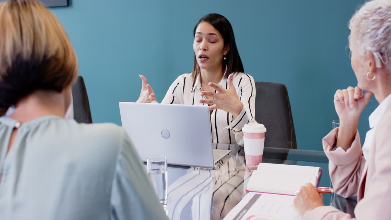 Discussing project details, woman using laptop and talking to colleagues in meeting