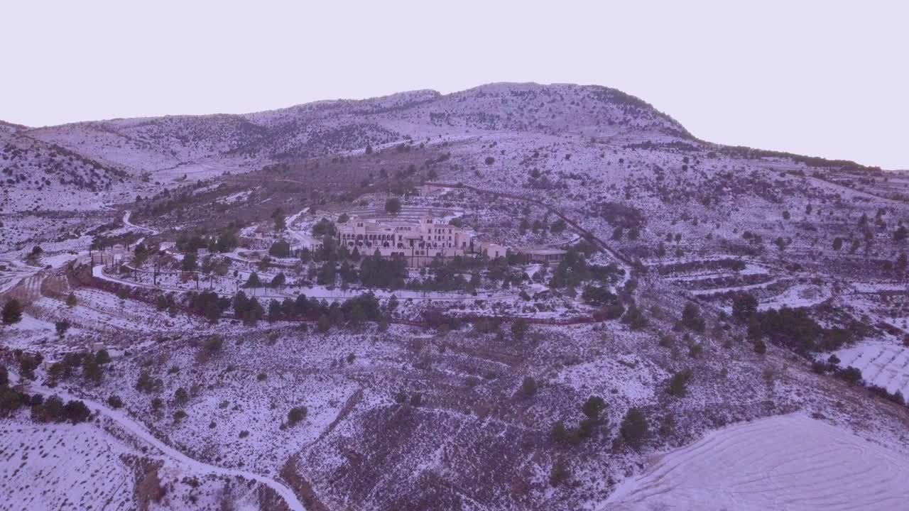 Drone panning left in the mountains in spain with snow and a hotel