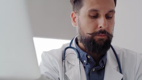 Handheld-view-of-male-doctor-checking-medical-results-on-laptop