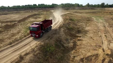 red dump truck driving through a quarry