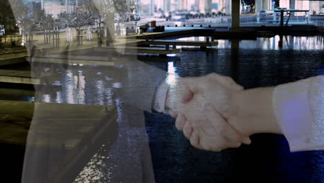 mid section of businessman and businesswoman shaking hands against cityscape
